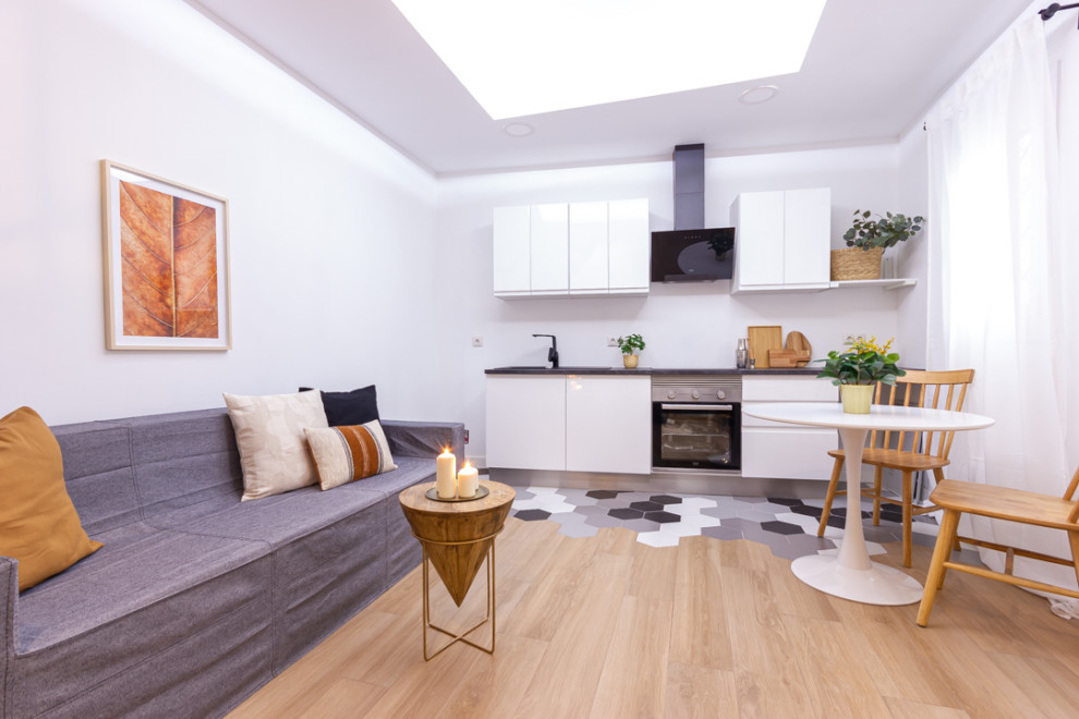 Foto de sala de estar tipo loft urbana pequeña sin televisor con paredes blancas, suelo de madera en tonos medios y suelo marrón