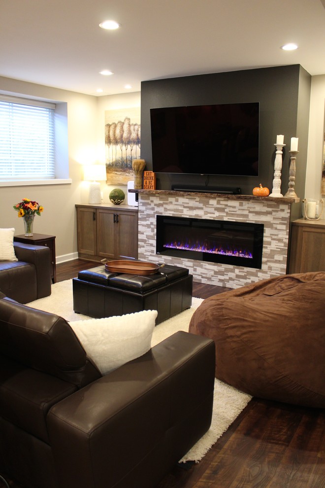 Design ideas for a large country fully buried basement in Milwaukee with beige walls, vinyl floors, a hanging fireplace, a tile fireplace surround and brown floor.