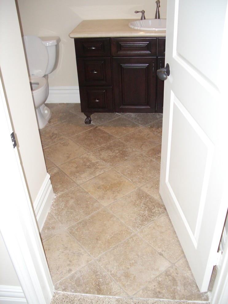 This is an example of a mid-sized mediterranean 3/4 bathroom in Los Angeles with furniture-like cabinets, dark wood cabinets, an alcove shower, a one-piece toilet, multi-coloured tile, stone tile, beige walls, travertine floors, a drop-in sink, concrete benchtops, multi-coloured floor, a hinged shower door, beige benchtops and a freestanding tub.