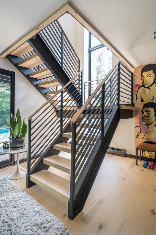Imagen de escalera en U contemporánea pequeña con escalones de madera, contrahuellas de metal y barandilla de madera