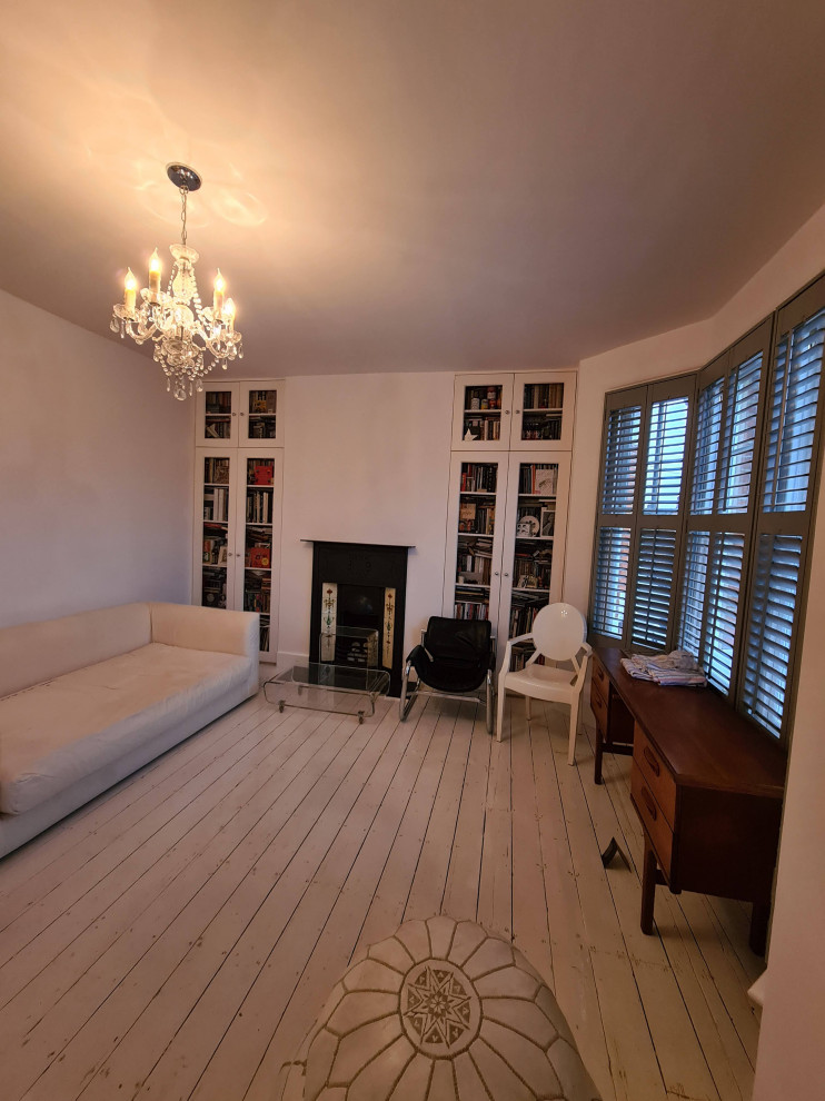 Mid-sized traditional open concept living room in London with a music area, white walls, painted wood floors, a standard fireplace, a metal fireplace surround, a freestanding tv, white floor and recessed.