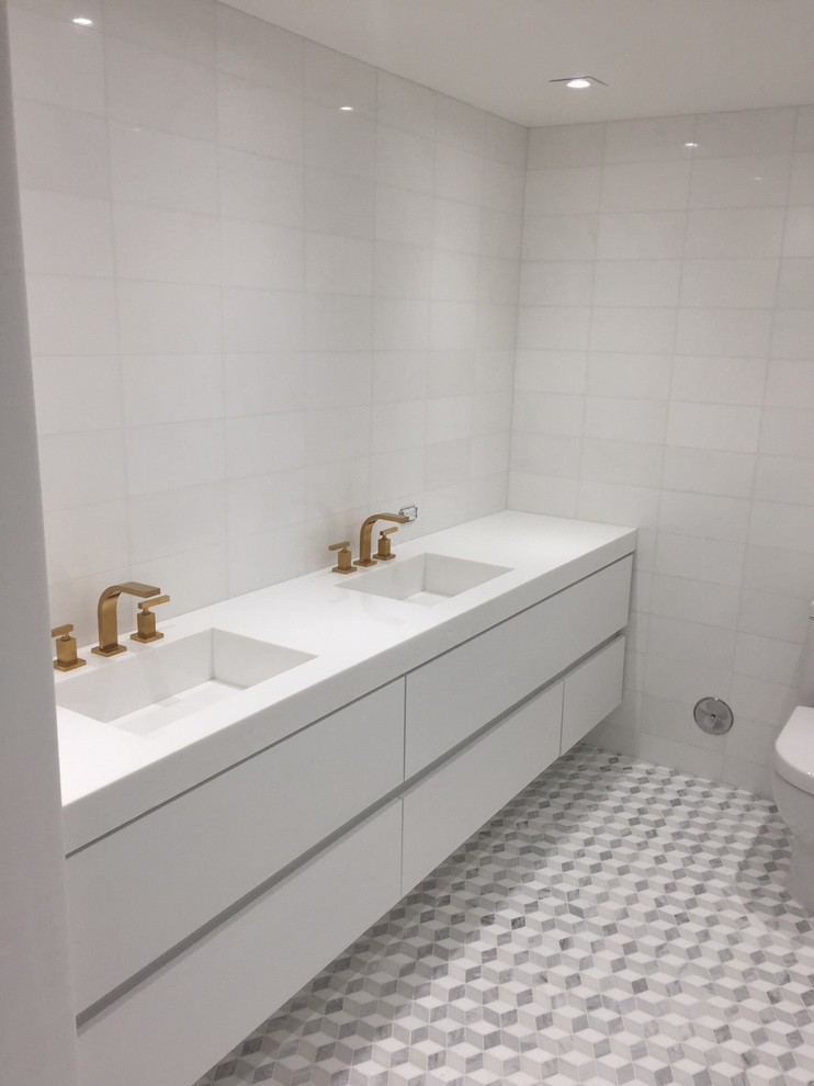 Inspiration for a mid-sized transitional master bathroom in Miami with flat-panel cabinets, white cabinets, white tile, marble, engineered quartz benchtops, an alcove shower, a one-piece toilet, white walls, marble floors, an integrated sink, white floor and a hinged shower door.