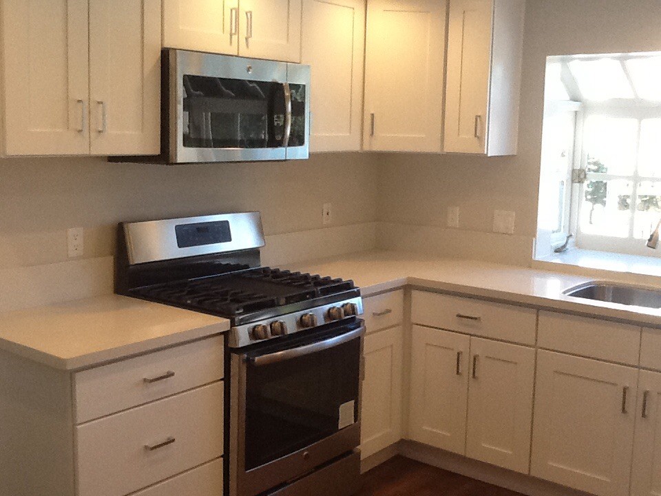 Inspiration for a mid-sized transitional medium tone wood floor and brown floor kitchen remodel in Orange County with an undermount sink, shaker cabinets, white cabinets, quartz countertops, stainless steel appliances and white countertops