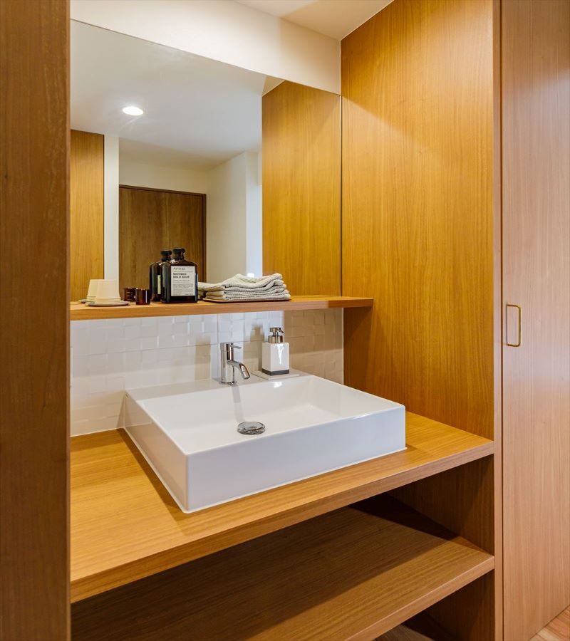 神戸にある中くらいなモダンスタイルのおしゃれなトイレ・洗面所 (白いタイル、無垢フローリング、茶色い床、ブラウンの洗面カウンター、クロスの天井) の写真
