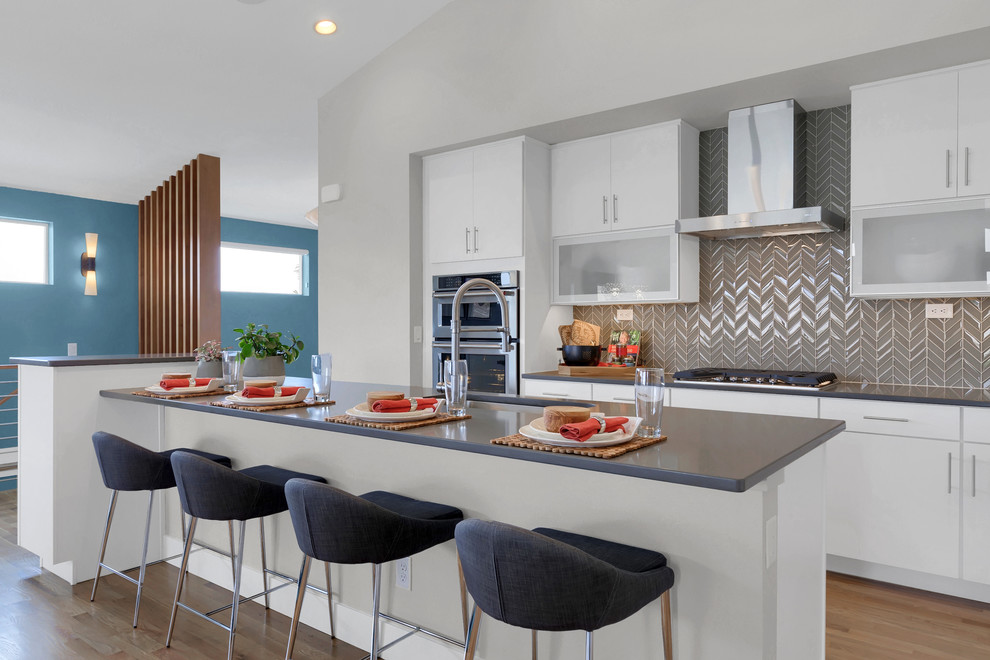 Design ideas for a large contemporary kitchen in Denver with an undermount sink, flat-panel cabinets, white cabinets, quartz benchtops, stainless steel appliances, light hardwood floors, with island, grey splashback, beige floor and grey benchtop.