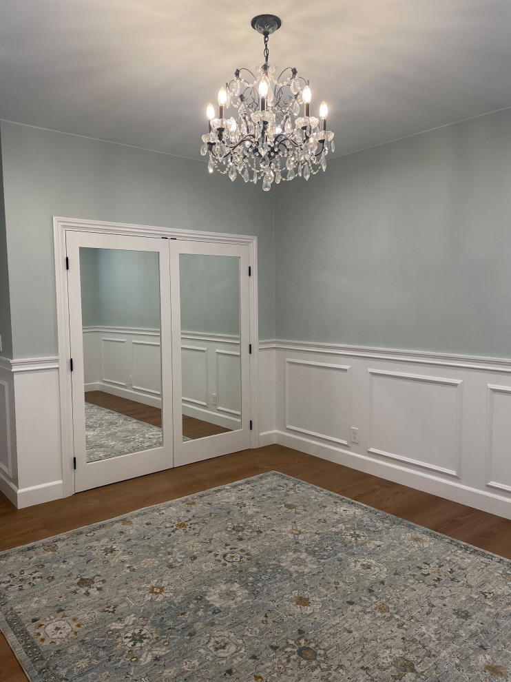 Immagine di una grande camera degli ospiti chic con pareti blu, pavimento in laminato, pavimento marrone e boiserie