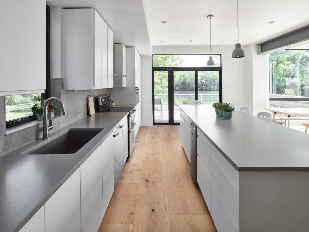 Contemporary kitchen in Philadelphia with medium hardwood floors, brown floor, a drop-in sink, grey splashback, limestone splashback and grey benchtop.