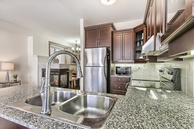 Inspiration for a mid-sized transitional u-shaped eat-in kitchen remodel in Toronto with a double-bowl sink, recessed-panel cabinets, medium tone wood cabinets, stainless steel appliances and a peninsula