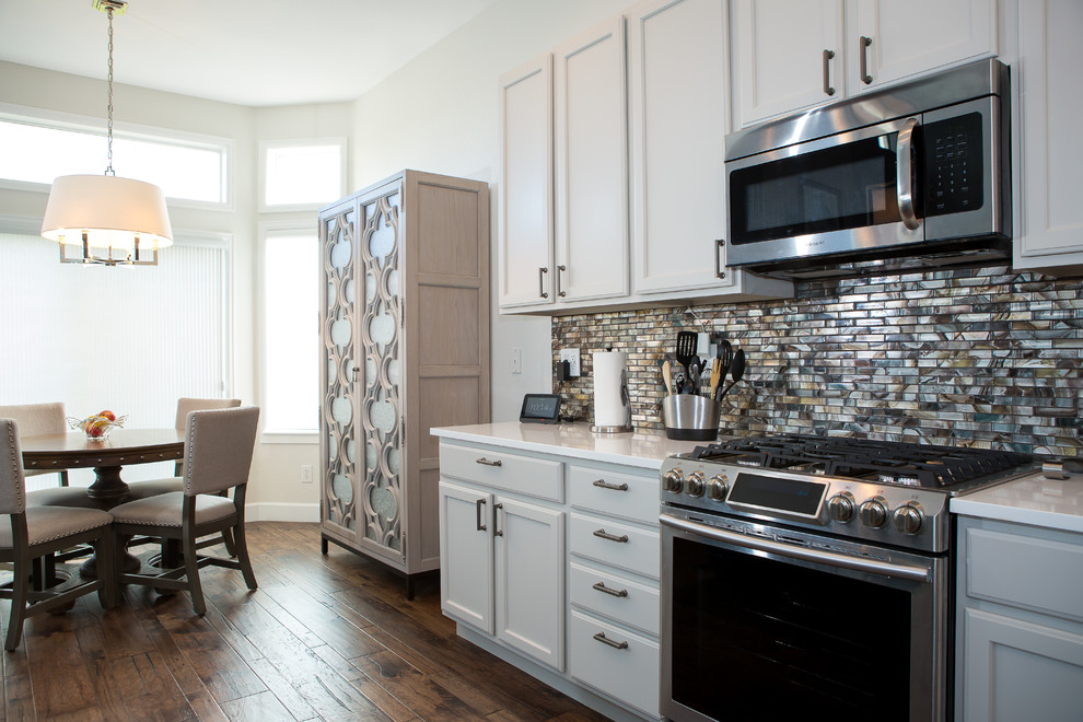 Open concept kitchen - mid-sized transitional l-shaped dark wood floor and brown floor open concept kitchen idea in Denver with a farmhouse sink, shaker cabinets, white cabinets, marble countertops, metallic backsplash, matchstick tile backsplash, paneled appliances, an island and gray countertops