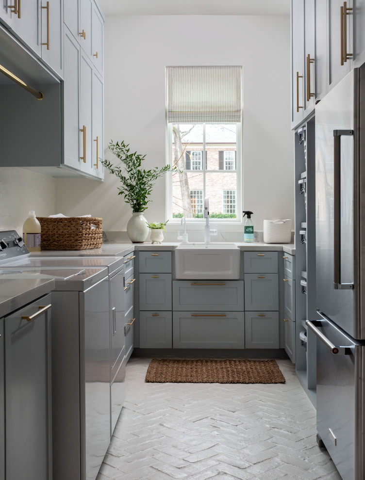 Inspiration for a huge transitional u-shaped brick floor and white floor dedicated laundry room remodel in Houston with a farmhouse sink, recessed-panel cabinets, blue cabinets, white walls, a side-by-side washer/dryer and white countertops