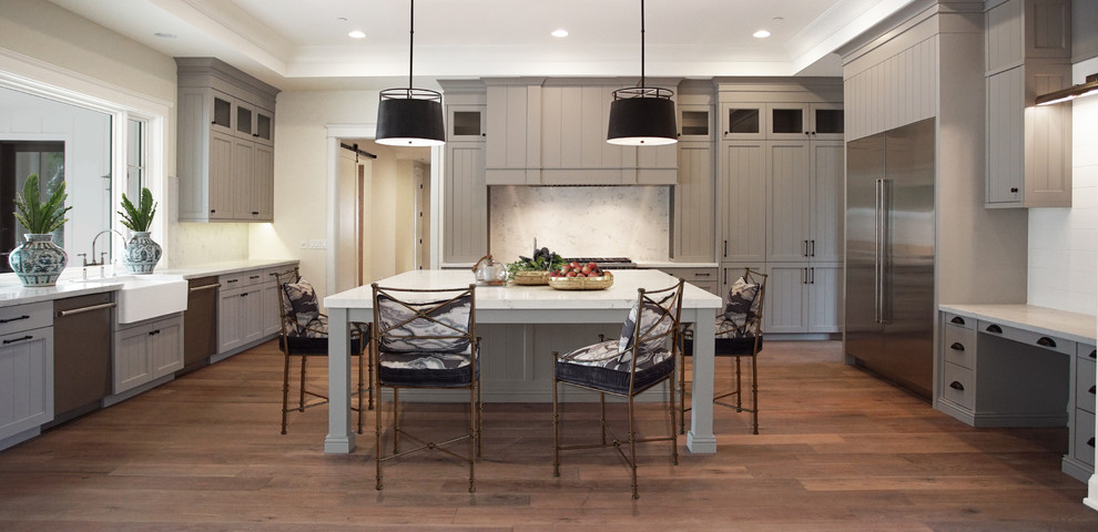Large traditional l-shaped eat-in kitchen in Phoenix with a farmhouse sink, louvered cabinets, grey cabinets, quartzite benchtops, white splashback, stone slab splashback, white appliances, dark hardwood floors, with island and brown floor.
