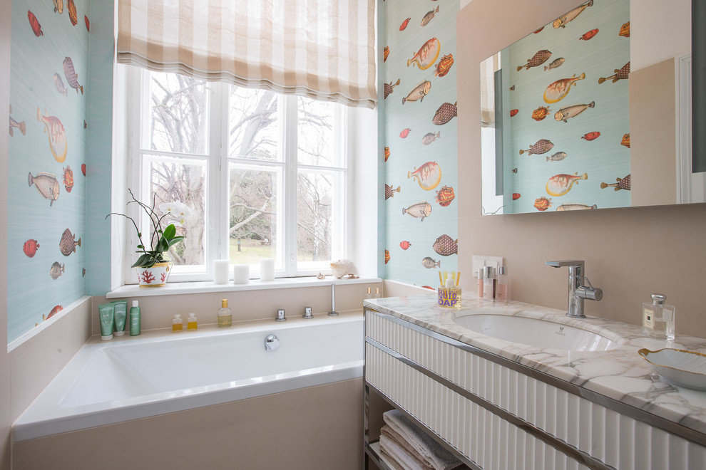 Maritimes Badezimmer mit Einbaubadewanne, bunten Wänden, Unterbauwaschbecken, weißen Schränken und Marmor-Waschbecken/Waschtisch in Sonstige