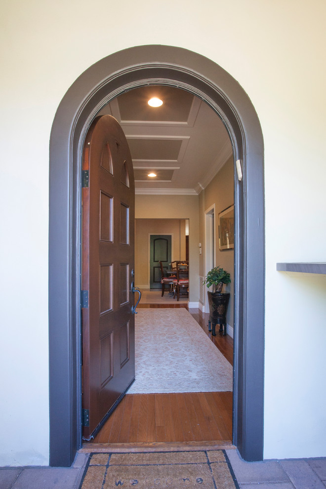 Inspiration for a large mediterranean front door in Los Angeles with beige walls, medium hardwood floors, a single front door and a dark wood front door.