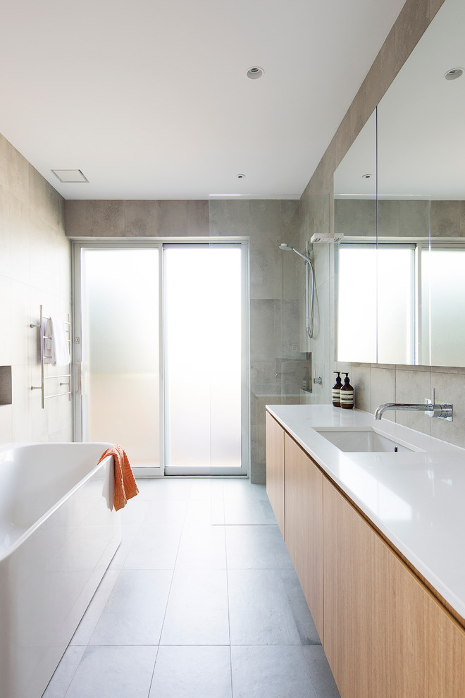 Large contemporary kids bathroom in Sydney with light wood cabinets, a freestanding tub, a curbless shower, gray tile, porcelain tile, grey walls, ceramic floors, an undermount sink and solid surface benchtops.