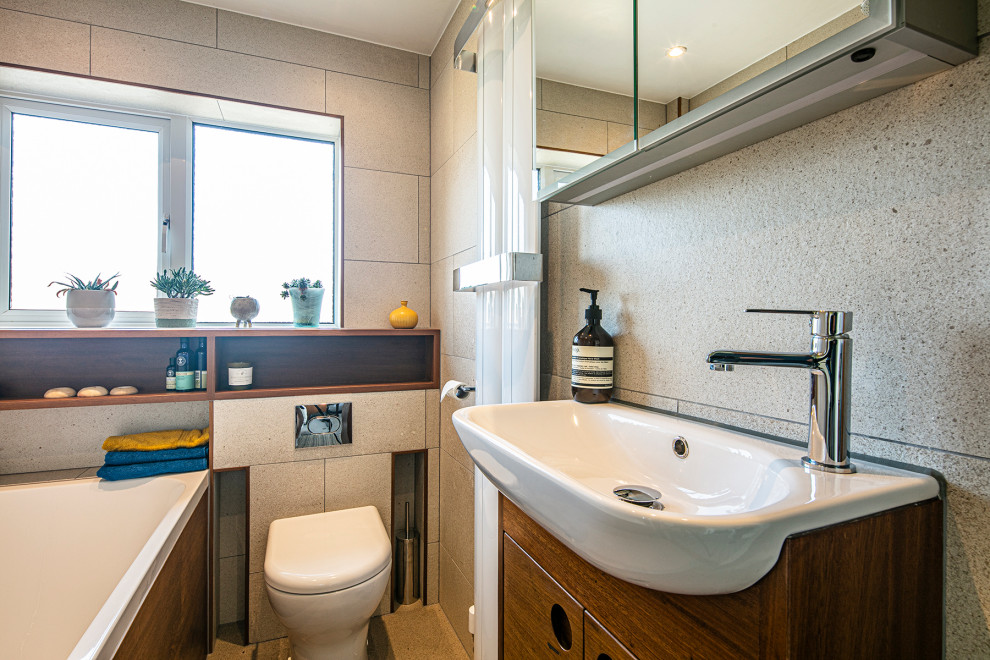 This is an example of a small bohemian family bathroom in Other with flat-panel cabinets, dark wood cabinets, a built-in bath, a shower/bath combination, beige tiles, stone slabs, beige walls, a hinged door, a single sink and a built in vanity unit.