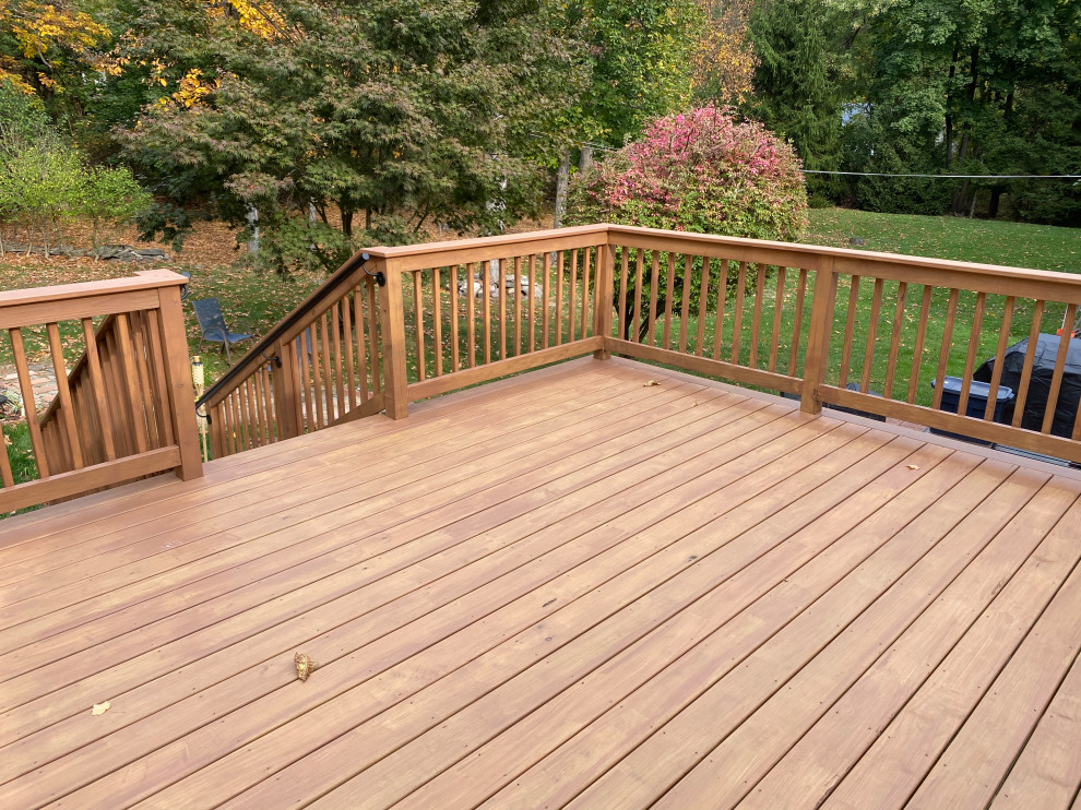 This is an example of a mid-sized traditional backyard and ground level deck in New York with no cover and wood railing.