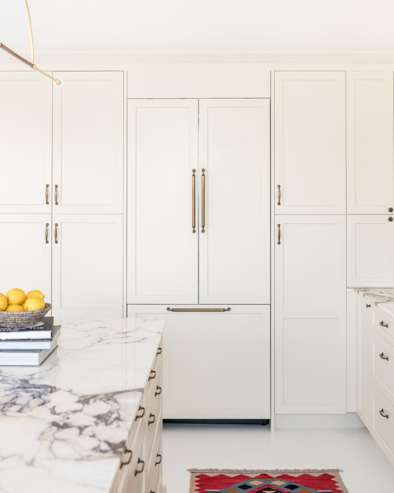 Inspiration for a large transitional u-shaped eat-in kitchen in Boston with a farmhouse sink, shaker cabinets, white cabinets, marble benchtops, white splashback, marble splashback, panelled appliances, with island, white floor and white benchtop.