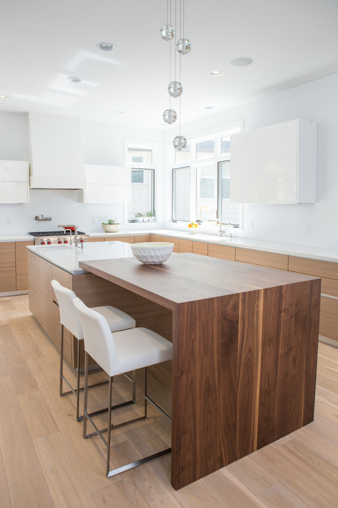 Photo of a transitional l-shaped eat-in kitchen in Portland with an undermount sink, flat-panel cabinets, light wood cabinets, quartz benchtops, panelled appliances, light hardwood floors and with island.