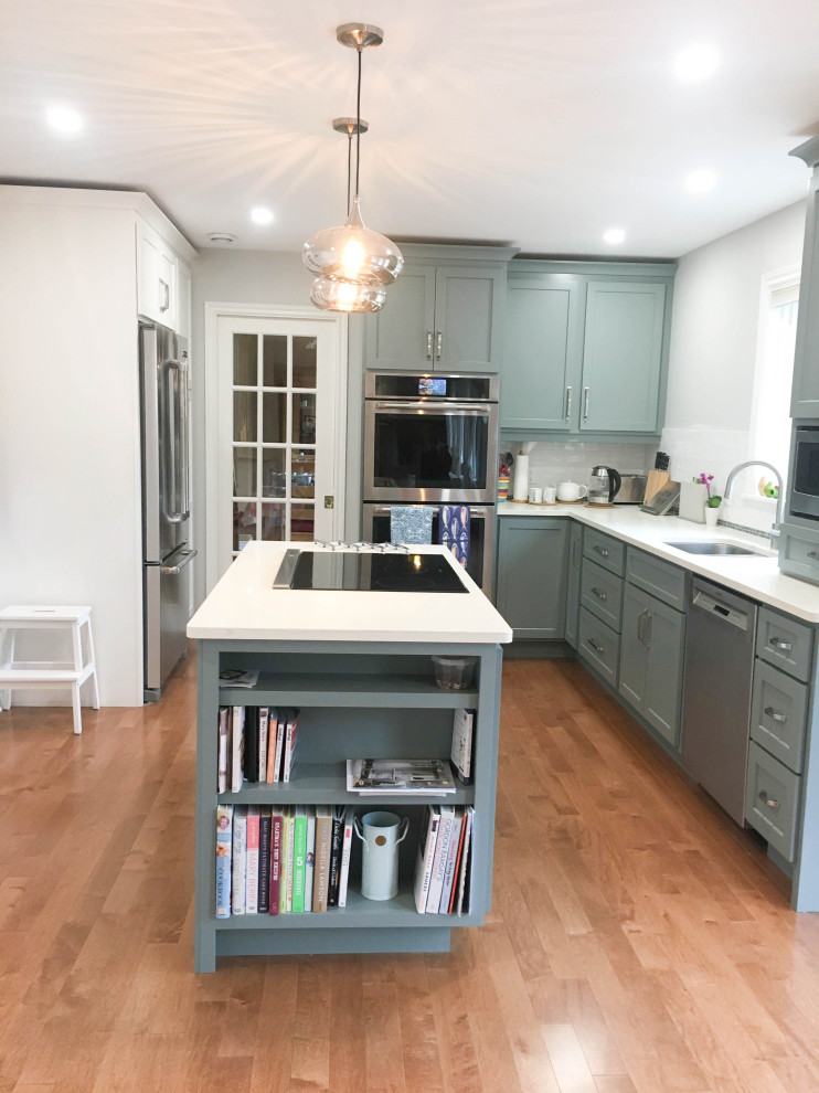 Example of a mid-sized transitional l-shaped medium tone wood floor and brown floor enclosed kitchen design with a double-bowl sink, shaker cabinets, gray cabinets, quartz countertops, white backsplash, porcelain backsplash, stainless steel appliances, an island and white countertops