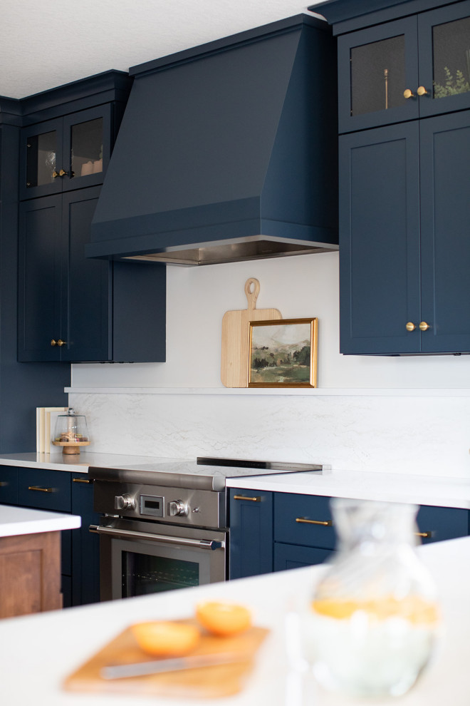 Inspiration for a large transitional light wood floor kitchen remodel with an undermount sink, shaker cabinets, blue cabinets, quartz countertops, white backsplash, quartz backsplash, stainless steel appliances, an island and white countertops
