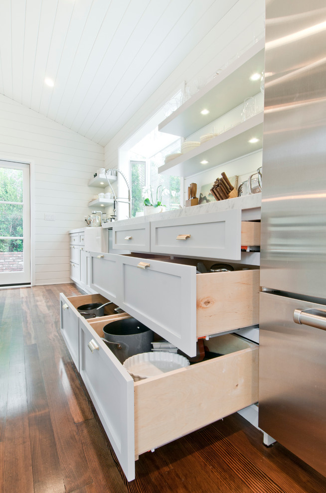 Mid-sized country galley eat-in kitchen in Los Angeles with a farmhouse sink, shaker cabinets, white cabinets, marble benchtops, white splashback, timber splashback, stainless steel appliances, painted wood floors and with island.