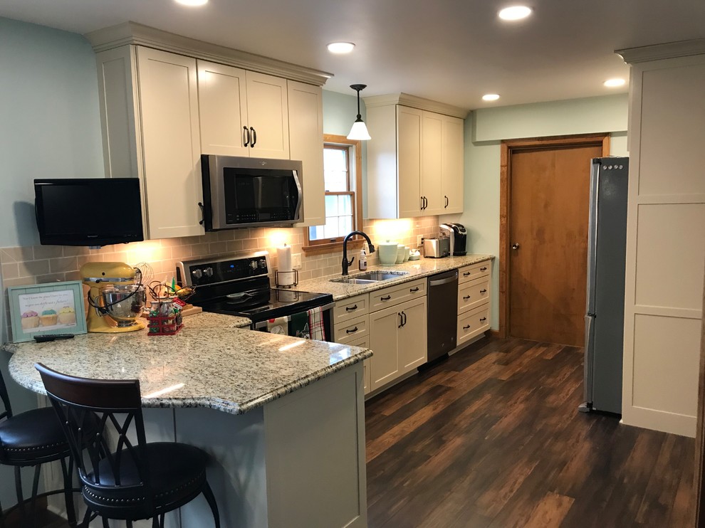 This is an example of a mid-sized traditional galley separate kitchen in Other with an undermount sink, shaker cabinets, beige cabinets, granite benchtops, stainless steel appliances and a peninsula.
