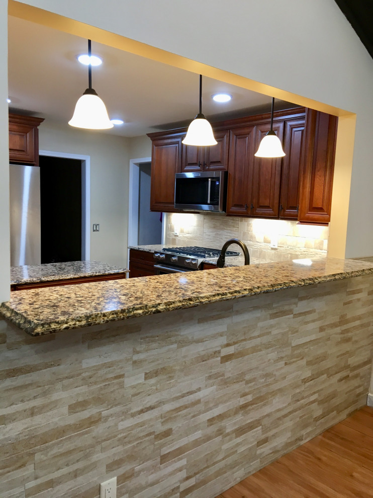Large transitional l-shaped vinyl floor and brown floor eat-in kitchen photo in Detroit with an undermount sink, raised-panel cabinets, medium tone wood cabinets, quartz countertops, beige backsplash, travertine backsplash, stainless steel appliances, an island and multicolored countertops
