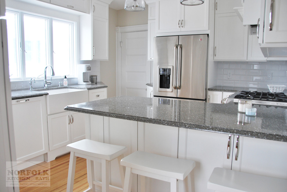 Small transitional u-shaped light wood floor eat-in kitchen photo in Boston with a farmhouse sink, recessed-panel cabinets, white cabinets, quartz countertops, white backsplash, subway tile backsplash, stainless steel appliances and a peninsula