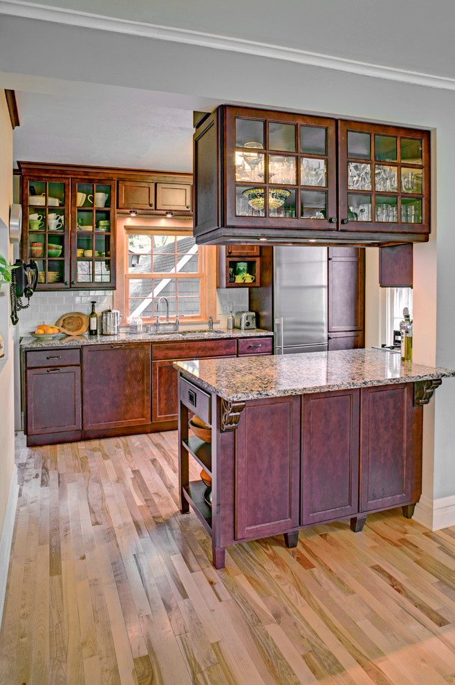 Example of a mid-sized transitional galley medium tone wood floor eat-in kitchen design with an undermount sink, flat-panel cabinets, medium tone wood cabinets, quartz countertops, white backsplash, subway tile backsplash, stainless steel appliances and an island