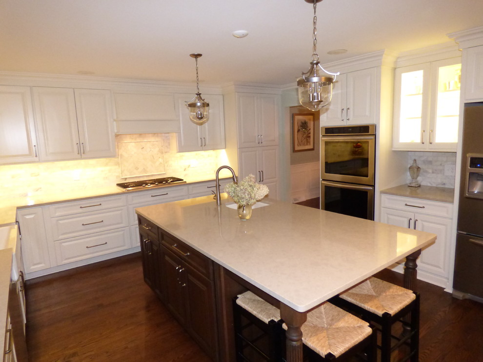 Large transitional u-shaped dark wood floor eat-in kitchen photo in Chicago with a farmhouse sink, raised-panel cabinets, white cabinets, quartz countertops, gray backsplash, stone tile backsplash, stainless steel appliances and an island