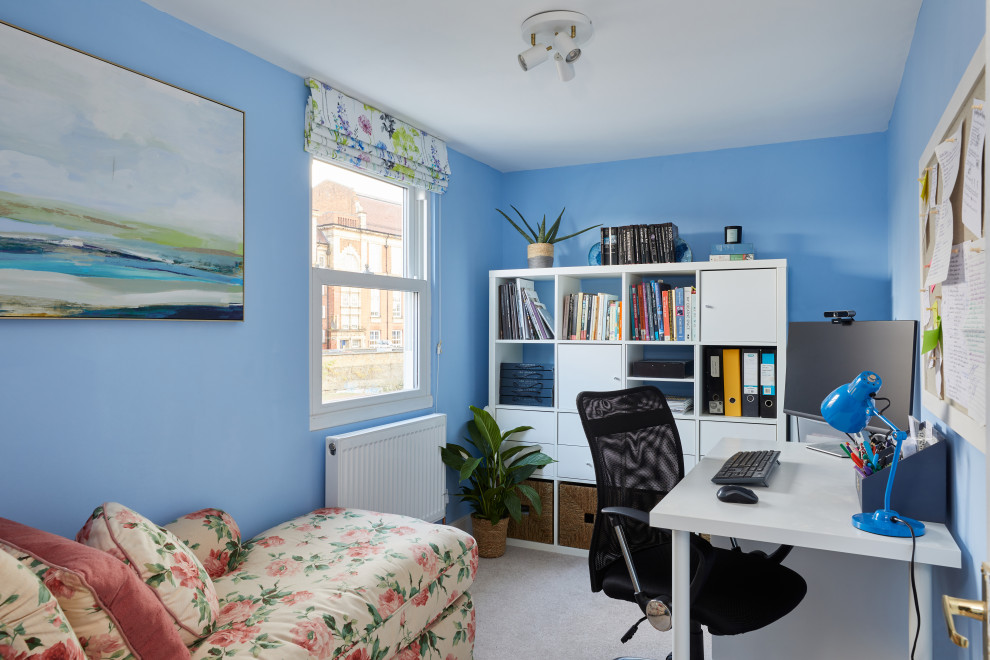 Idéer för små funkis hemmabibliotek, med blå väggar, heltäckningsmatta, ett fristående skrivbord och beiget golv