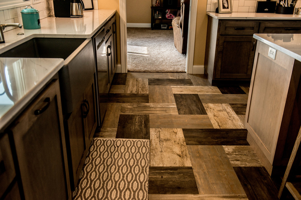 Large transitional l-shaped vinyl floor and multicolored floor open concept kitchen photo with a farmhouse sink, shaker cabinets, gray cabinets, quartz countertops, white backsplash, subway tile backsplash, stainless steel appliances, an island and white countertops