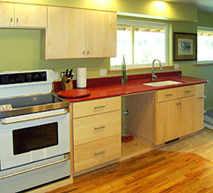 Kitchen - galley brown floor kitchen idea with an undermount sink, flat-panel cabinets, an island and red countertops