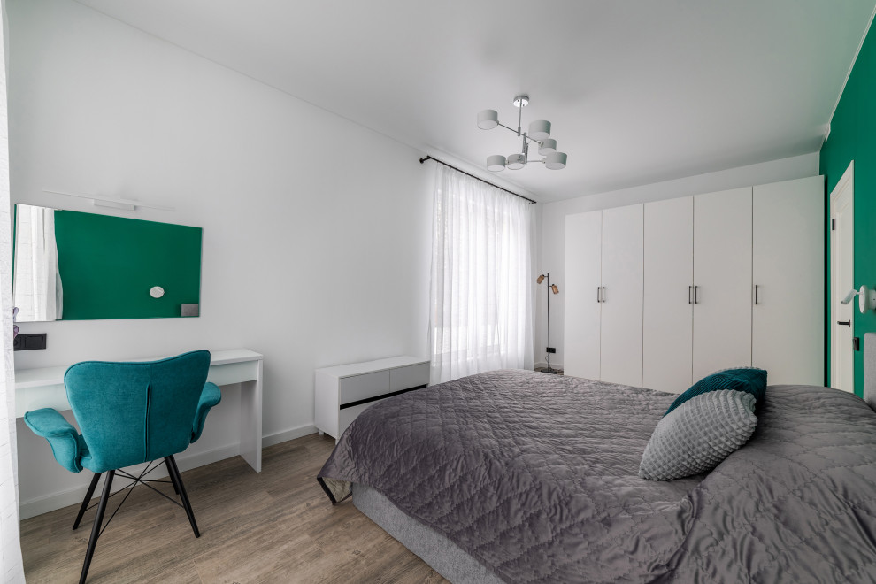 На фото: большая гостевая спальня (комната для гостей) в стиле модернизм с зелеными стенами, полом из ламината, коричневым полом и акцентной стеной без камина с