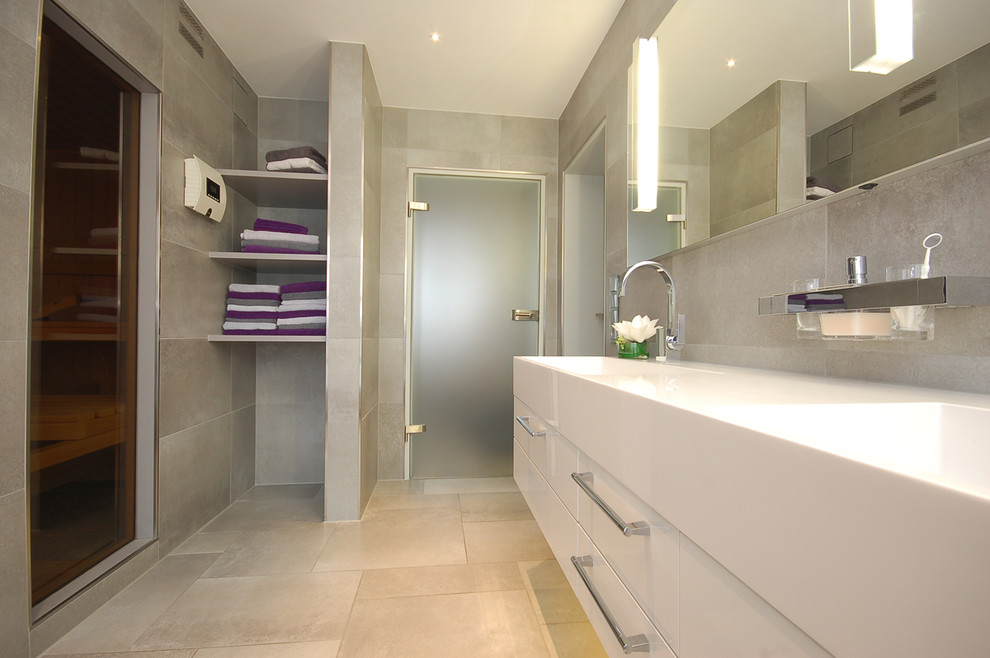 Badezimmer With weißen Schränken, grauen Fliesen, grauer Wandfarbe and integriertem Waschbecken in Bremen