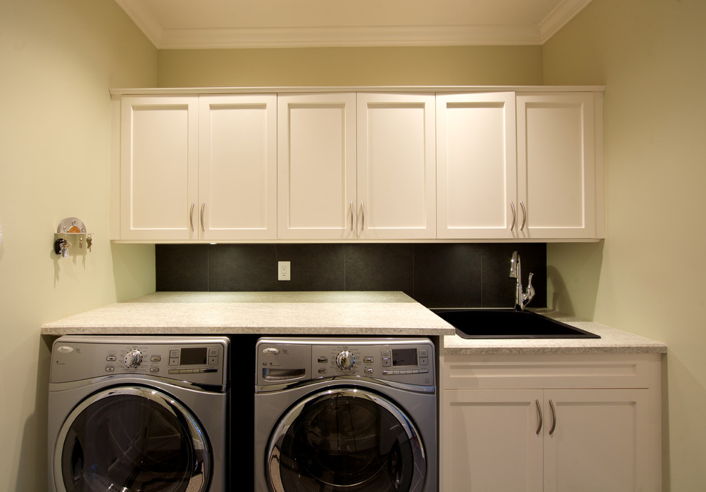 Design ideas for a traditional galley dedicated laundry room in Vancouver with a drop-in sink, shaker cabinets, white cabinets, green walls and a side-by-side washer and dryer.