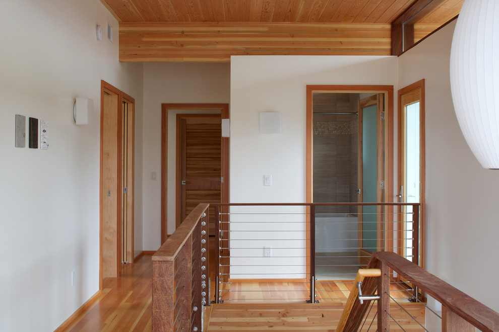 This is an example of a mid-sized contemporary hallway in Grand Rapids with white walls and medium hardwood floors.