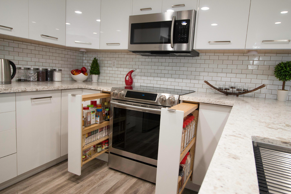 This is an example of a small contemporary l-shaped separate kitchen in San Francisco with an undermount sink, flat-panel cabinets, white cabinets, limestone benchtops, white splashback, subway tile splashback, stainless steel appliances, light hardwood floors, a peninsula, beige floor and white benchtop.