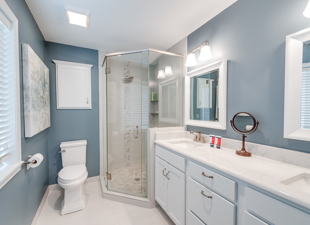 Design ideas for a small transitional master bathroom in Kansas City with shaker cabinets, white cabinets, a corner shower, a one-piece toilet, blue tile, pebble tile, blue walls, ceramic floors, an undermount sink, marble benchtops, white floor and a hinged shower door.