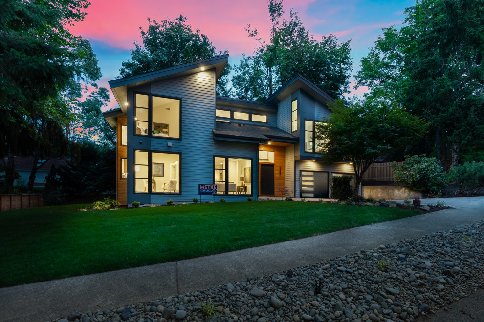 Inspiration pour une grande façade de maison bleue design à un étage avec un toit marron.