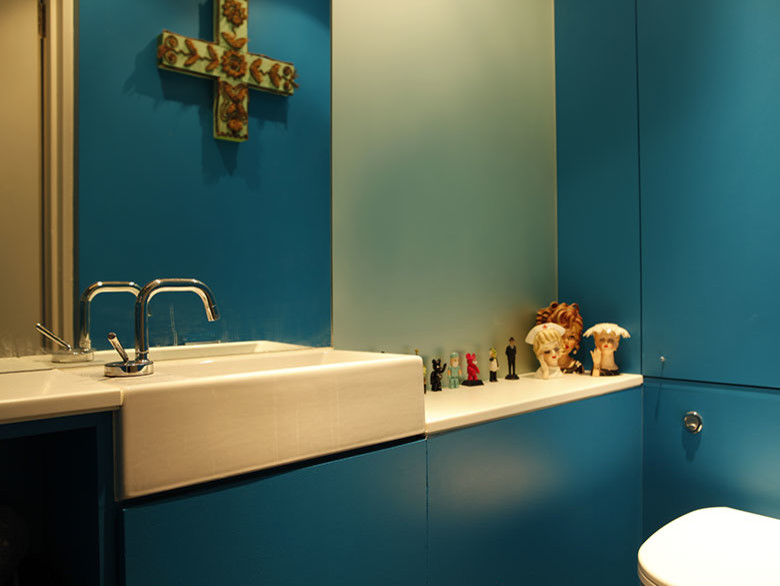 Small mediterranean bathroom with flat-panel cabinets, blue cabinets, glass sheet wall, ceramic floors, a drop-in sink, solid surface benchtops and brown floor.