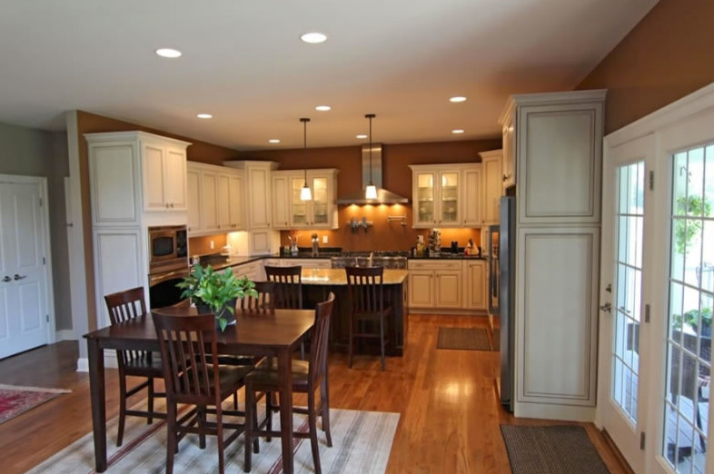 Photo of a large traditional u-shaped eat-in kitchen in Richmond with raised-panel cabinets, beige cabinets, granite benchtops, stainless steel appliances, medium hardwood floors and with island.