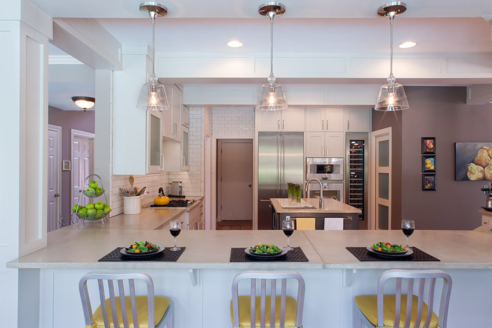 Inspiration for an expansive contemporary u-shaped open plan kitchen in Austin with an undermount sink, shaker cabinets, white cabinets, concrete benchtops, white splashback, subway tile splashback, stainless steel appliances, terra-cotta floors, with island and brown floor.