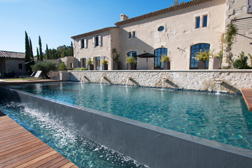 Large country rectangular infinity pool in Marseille with a water feature and decking.