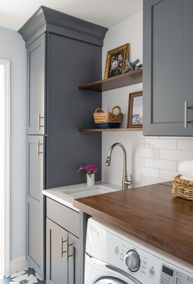 Transitional single-wall dedicated laundry room in Boston with an undermount sink, blue cabinets, quartz benchtops, white splashback, subway tile splashback, white walls, ceramic floors, a side-by-side washer and dryer and white benchtop.