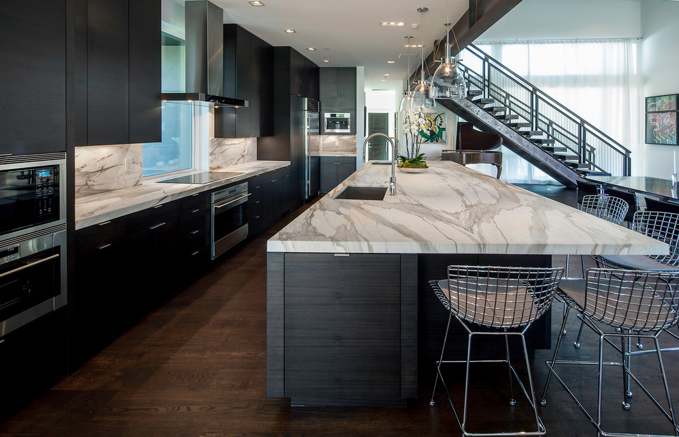 Contemporary galley kitchen in Salt Lake City with a single-bowl sink, flat-panel cabinets, black cabinets, white splashback, stone slab splashback and stainless steel appliances.