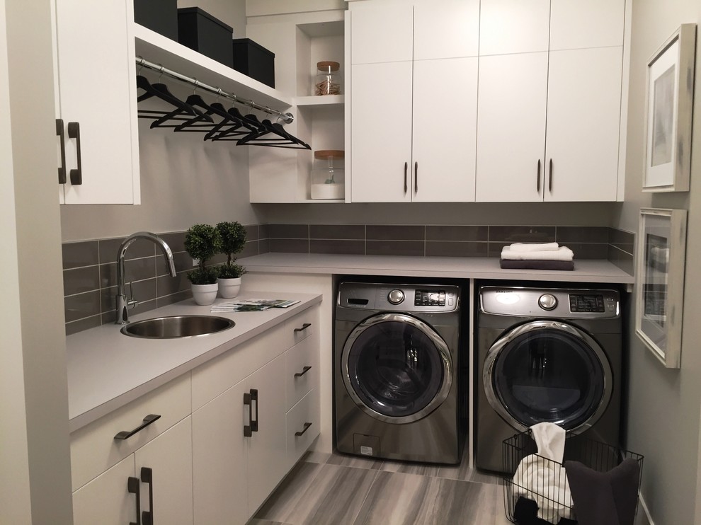 Inspiration for a mid-sized modern l-shaped dedicated laundry room in Calgary with a single-bowl sink, flat-panel cabinets, white cabinets, laminate benchtops and a side-by-side washer and dryer.