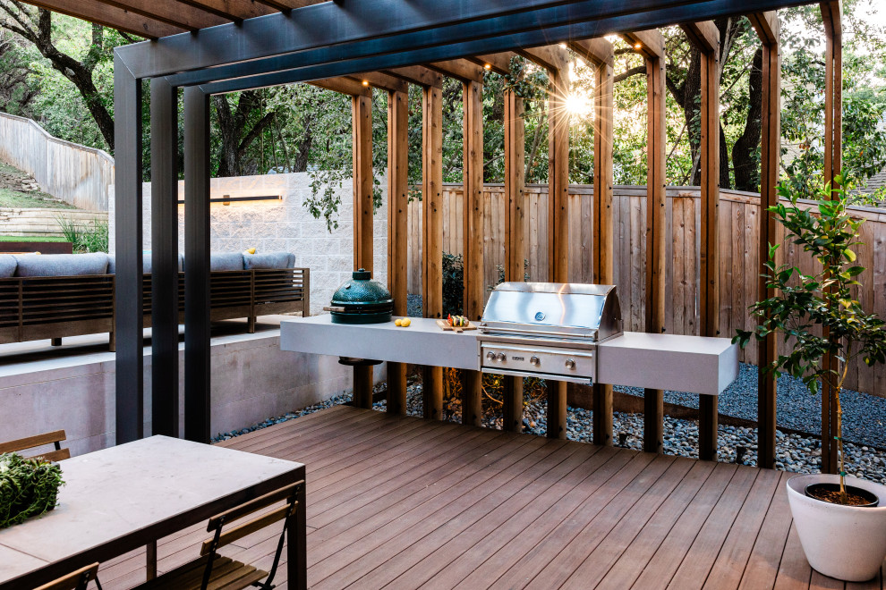 Example of a mid-sized backyard ground level outdoor kitchen deck design in Austin with a pergola