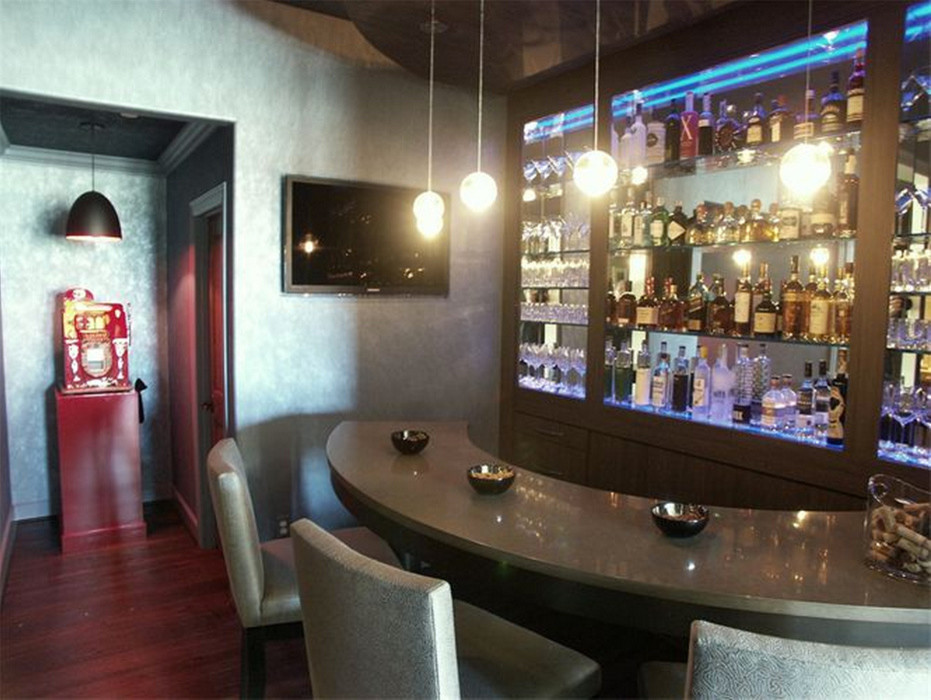 This is an example of a mid-sized traditional single-wall seated home bar in Seattle with open cabinets, solid surface benchtops, mirror splashback, dark hardwood floors, brown floor and grey benchtop.