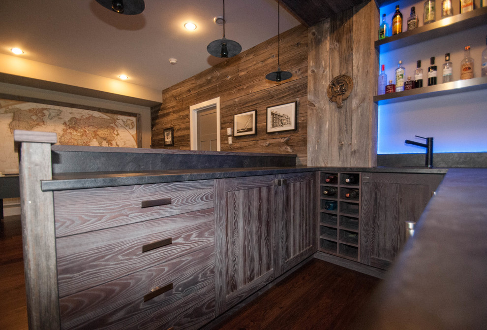 Design ideas for a large country u-shaped seated home bar in Other with a drop-in sink, shaker cabinets, light wood cabinets, concrete benchtops, blue splashback, glass sheet splashback, dark hardwood floors and brown floor.